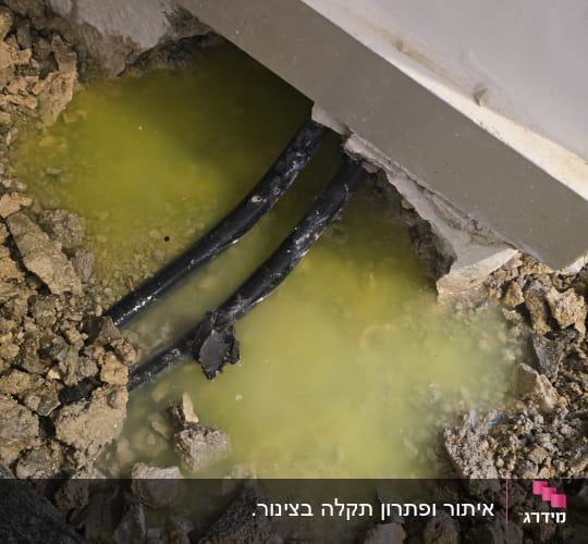 דליפה בצנרת עם מים צהובים ואדמה חשופה